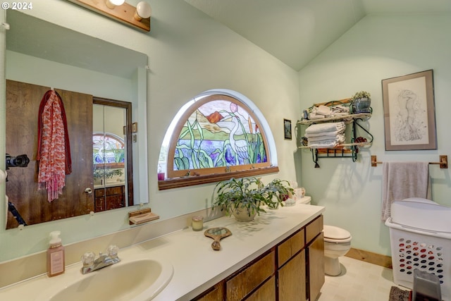 bathroom with lofted ceiling, toilet, and vanity