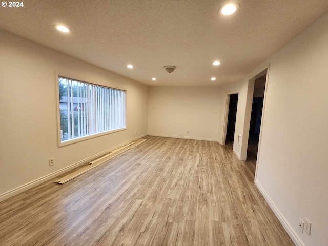 spare room with light wood-type flooring and a textured ceiling