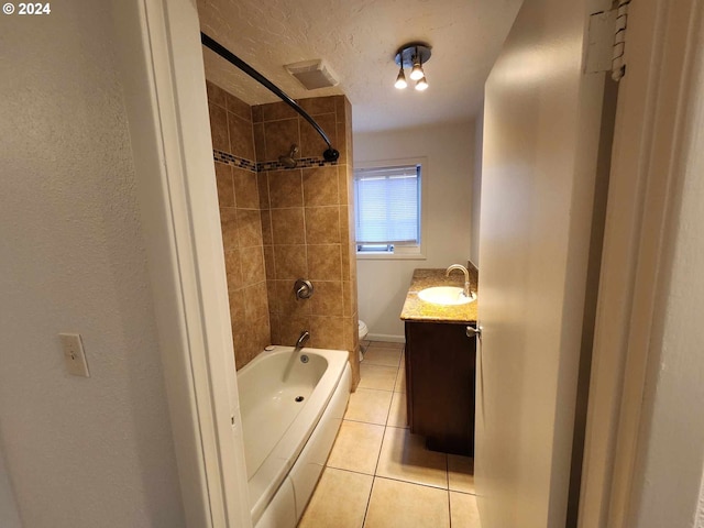 full bathroom featuring a textured ceiling, vanity, tile patterned flooring, toilet, and tiled shower / bath combo