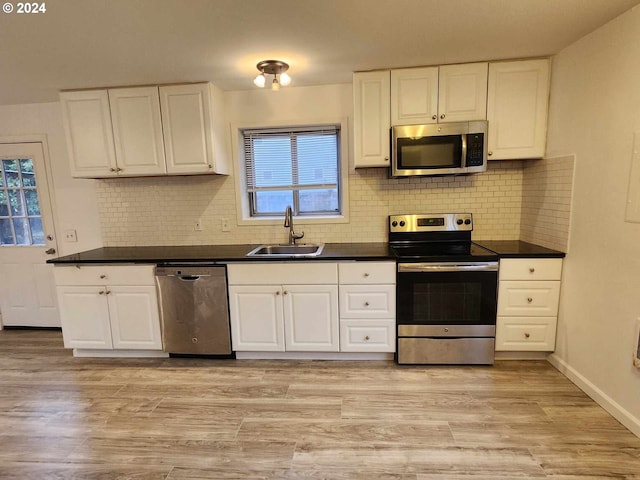 kitchen featuring appliances with stainless steel finishes, sink, decorative backsplash, light wood-type flooring, and white cabinets