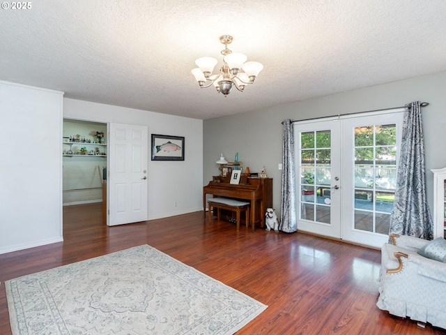 interior space with french doors, a textured ceiling, wood finished floors, baseboards, and a chandelier