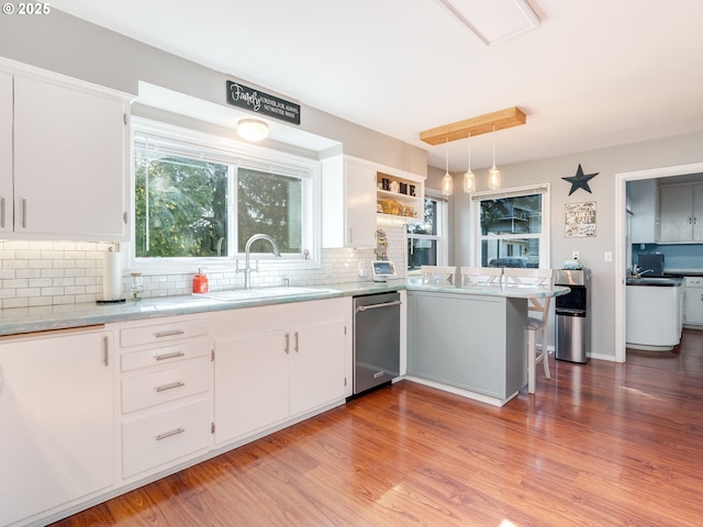 kitchen featuring white cabinets, decorative backsplash, a sink, and dishwasher