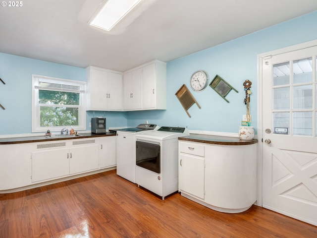 laundry area featuring light wood-type flooring, washer and clothes dryer, cabinet space, and a sink
