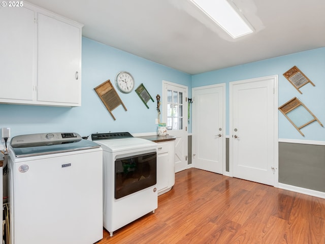 clothes washing area featuring cabinet space, separate washer and dryer, and light wood-style flooring