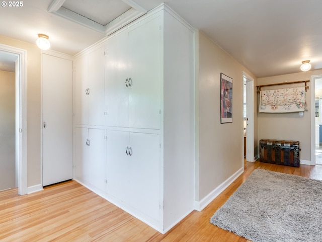 corridor featuring light wood-style floors, baseboards, and attic access