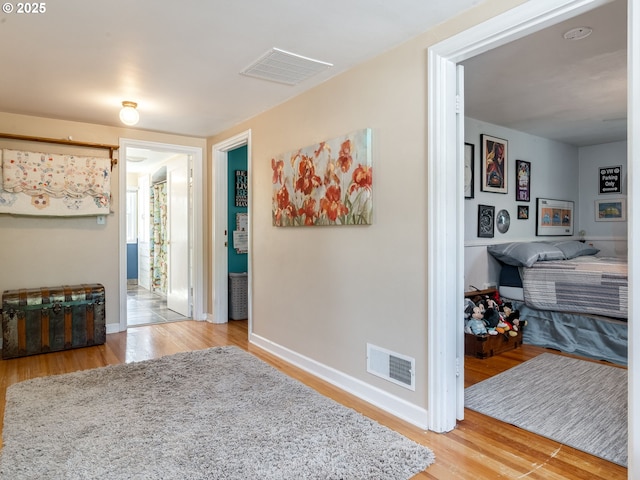 hall featuring visible vents, baseboards, and wood finished floors