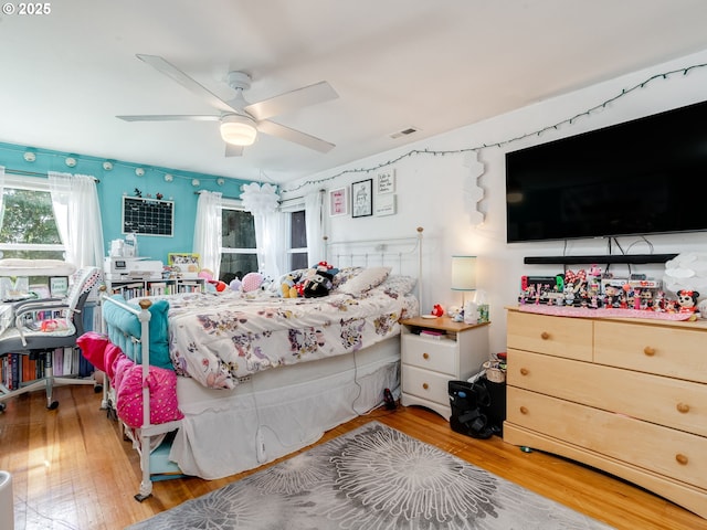 bedroom with a ceiling fan, wood finished floors, and visible vents
