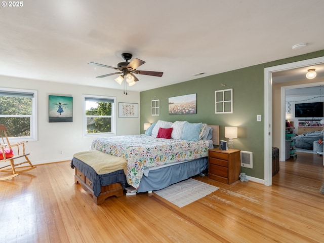 bedroom featuring a ceiling fan, baseboards, visible vents, and wood finished floors