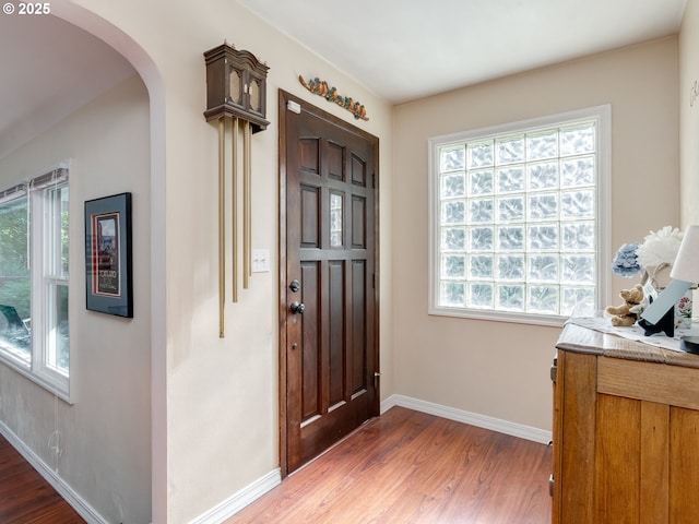 entrance foyer featuring arched walkways, plenty of natural light, and wood finished floors