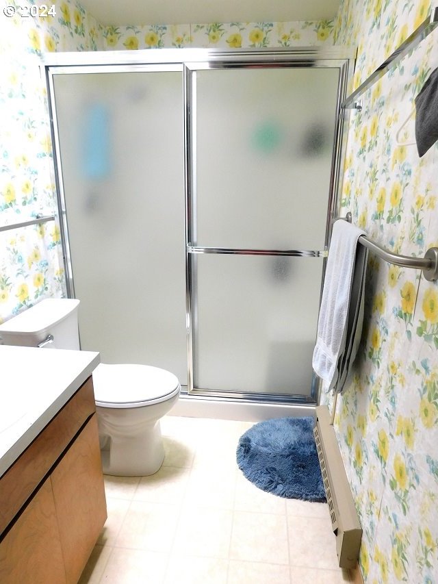 bathroom with tile patterned flooring, walk in shower, vanity, and toilet