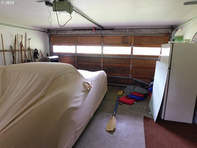 garage with a garage door opener and white refrigerator