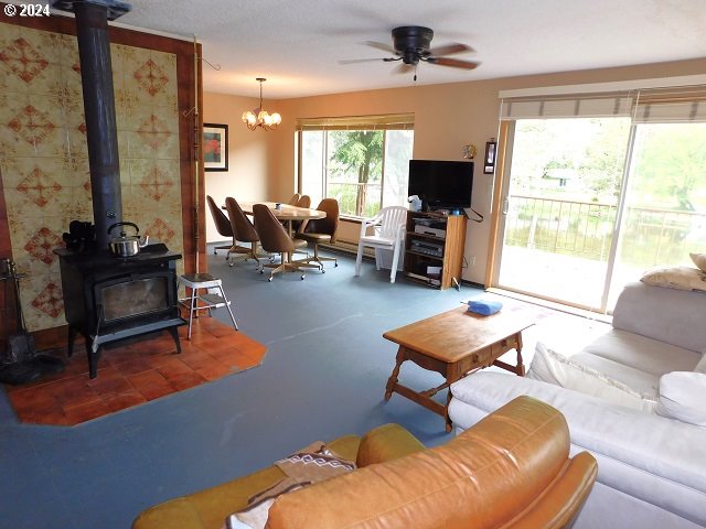 living room with ceiling fan with notable chandelier and a wood stove