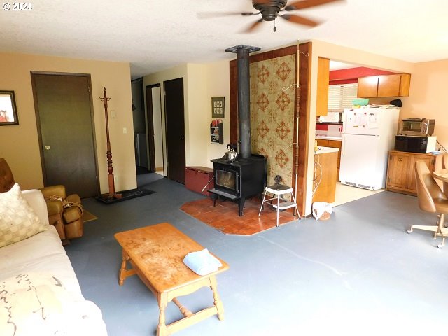 living room with a wood stove and ceiling fan