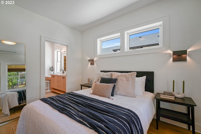 bedroom with hardwood / wood-style floors, ensuite bath, and sink