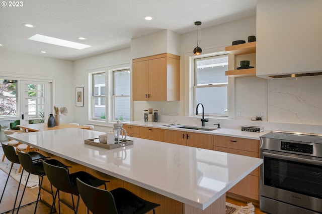 kitchen featuring decorative backsplash, hanging light fixtures, a kitchen island, stainless steel range, and sink