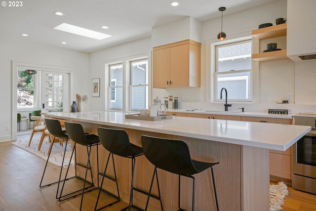 kitchen featuring pendant lighting, light brown cabinetry, a center island, and light wood-type flooring