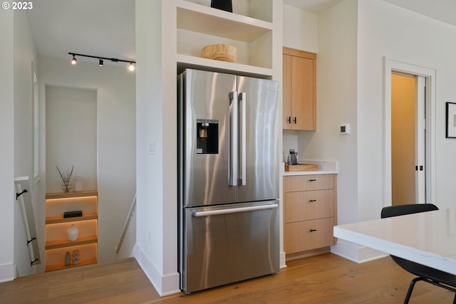 kitchen with light brown cabinets, stainless steel refrigerator with ice dispenser, light wood-type flooring, and rail lighting