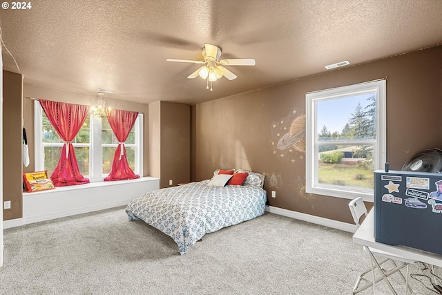 carpeted bedroom with a textured ceiling and ceiling fan with notable chandelier