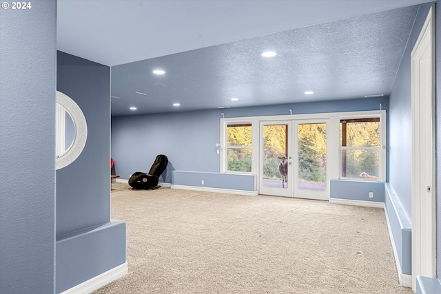 interior space with carpet, a textured ceiling, and french doors