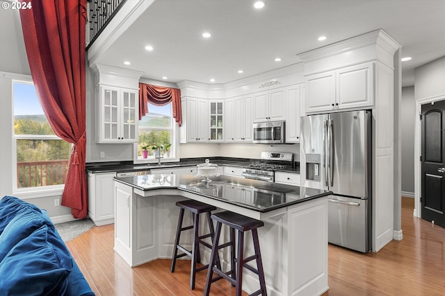 kitchen with a center island, appliances with stainless steel finishes, a kitchen breakfast bar, and white cabinetry