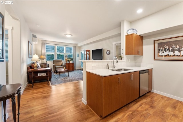 kitchen featuring a wall mounted AC, stainless steel dishwasher, light hardwood / wood-style flooring, and sink