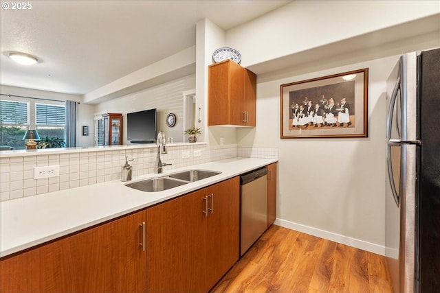 kitchen with appliances with stainless steel finishes, light hardwood / wood-style floors, backsplash, and sink