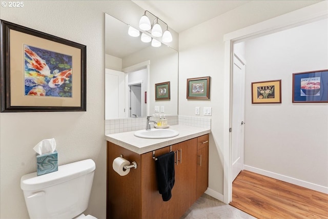 bathroom with toilet, wood-type flooring, vanity, and tasteful backsplash