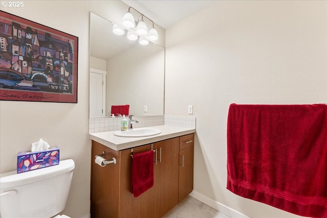 bathroom with toilet, tile patterned floors, vanity, and decorative backsplash