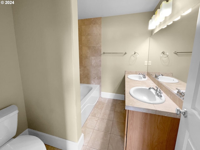 bathroom with a tub, toilet, vanity, and tile patterned floors