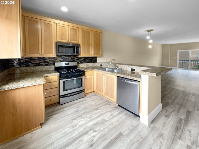 kitchen with kitchen peninsula, stainless steel appliances, sink, and light hardwood / wood-style floors