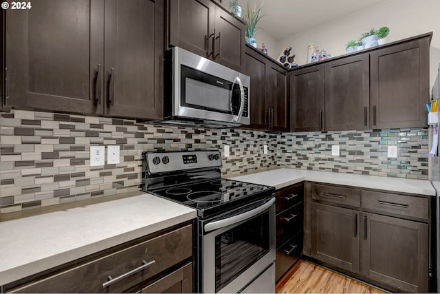 kitchen with dark brown cabinetry, stainless steel appliances, light hardwood / wood-style floors, and tasteful backsplash