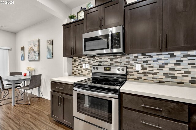 kitchen with appliances with stainless steel finishes, decorative backsplash, dark brown cabinetry, and light hardwood / wood-style flooring