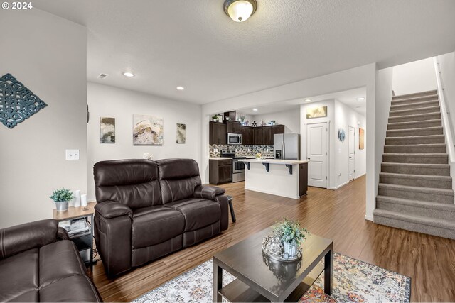 living room featuring recessed lighting, visible vents, wood finished floors, baseboards, and stairs