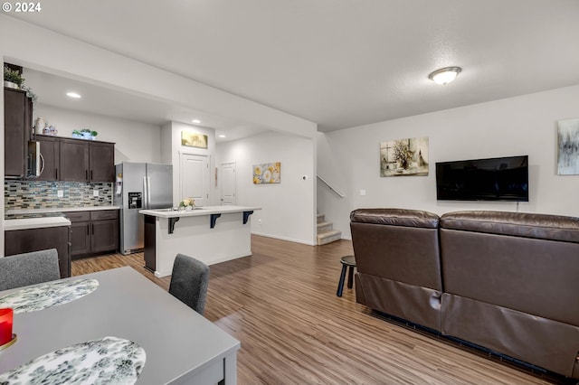 living area with recessed lighting, stairway, light wood-type flooring, and baseboards