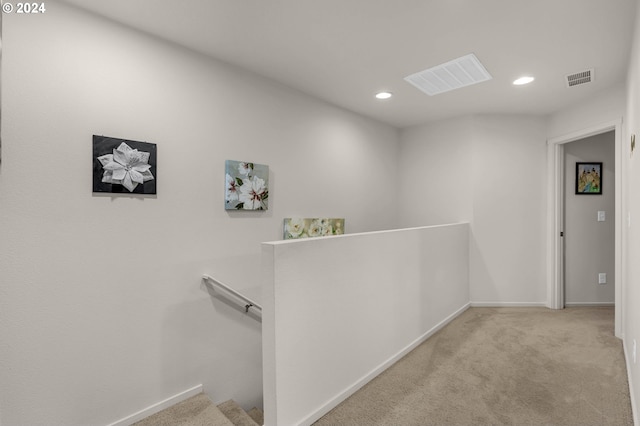 hallway featuring carpet, visible vents, and an upstairs landing