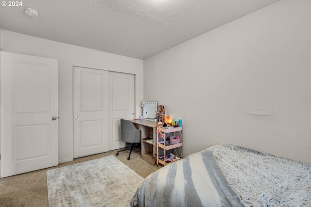 carpeted bedroom featuring a textured ceiling and a closet