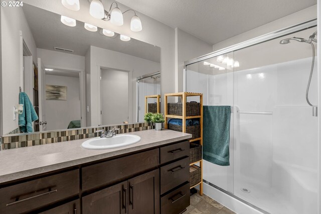 bathroom featuring vanity, an enclosed shower, and a textured ceiling