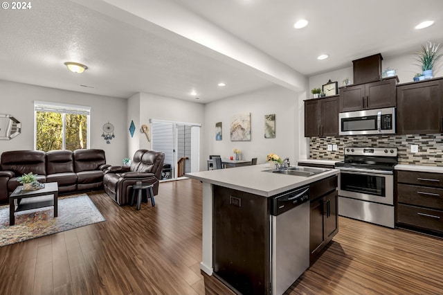 kitchen with stainless steel appliances, a center island with sink, sink, dark hardwood / wood-style floors, and dark brown cabinets