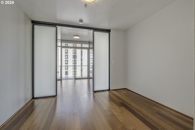 spare room featuring expansive windows and hardwood / wood-style flooring