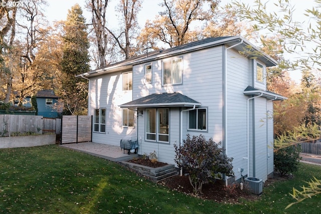 rear view of property with cooling unit, a patio area, and a lawn