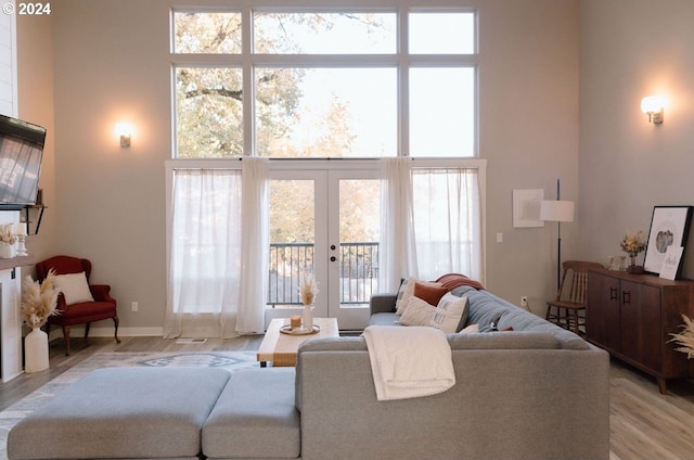 living room featuring a towering ceiling, french doors, and light wood-type flooring