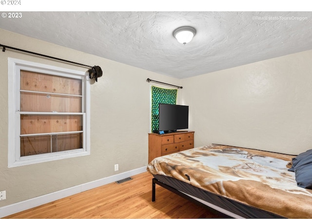 bedroom with hardwood / wood-style floors and a textured ceiling