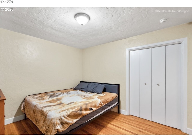 bedroom featuring a closet, a textured ceiling, and light hardwood / wood-style flooring