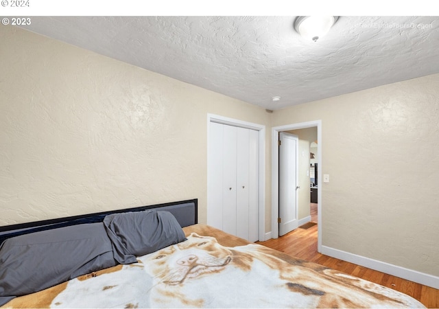 bedroom featuring a textured ceiling, light hardwood / wood-style floors, and a closet