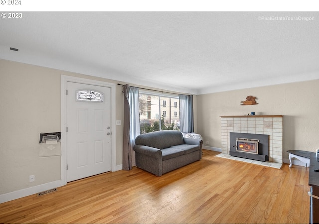 living room featuring a tile fireplace, hardwood / wood-style floors, and a textured ceiling