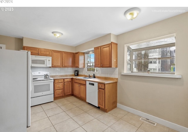 kitchen with tasteful backsplash, sink, light tile patterned floors, and white appliances