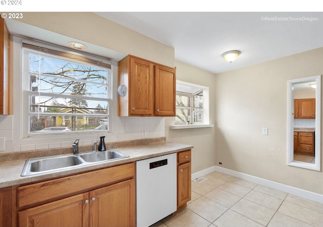 kitchen featuring backsplash, dishwasher, light tile patterned flooring, and sink