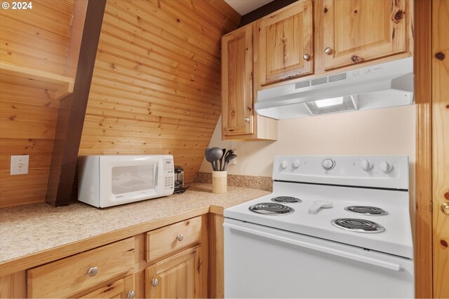 kitchen featuring white appliances, wooden walls, and light brown cabinets