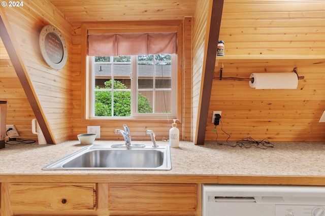 kitchen featuring light countertops, white dishwasher, a sink, wooden walls, and wooden ceiling