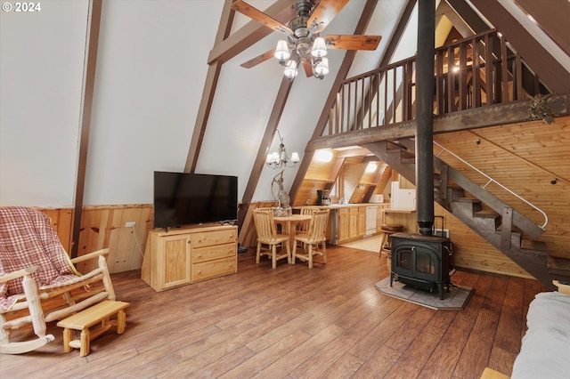 living room featuring beamed ceiling, hardwood / wood-style floors, wood walls, and a wood stove